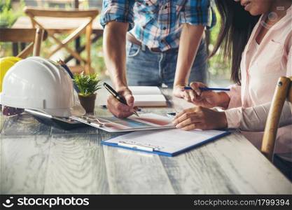 Civil construction engineer team meeting on construction site with teamwork wear safety suit trust team look at blue print on table consulting together safety hard hat construction engineer concept