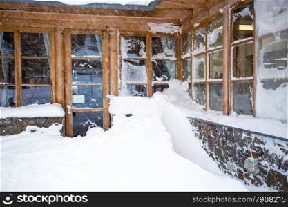 Classic Austrian wooden house with big windows covered by snow at snowstorm