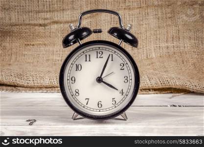 Classic black and white alarm clock on a wooden table