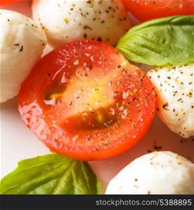 Classic caprese salad: tomato, mozzarella and basil leaves