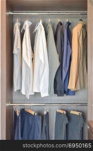 Classic color shirts are hanging in open wooden wardrobe