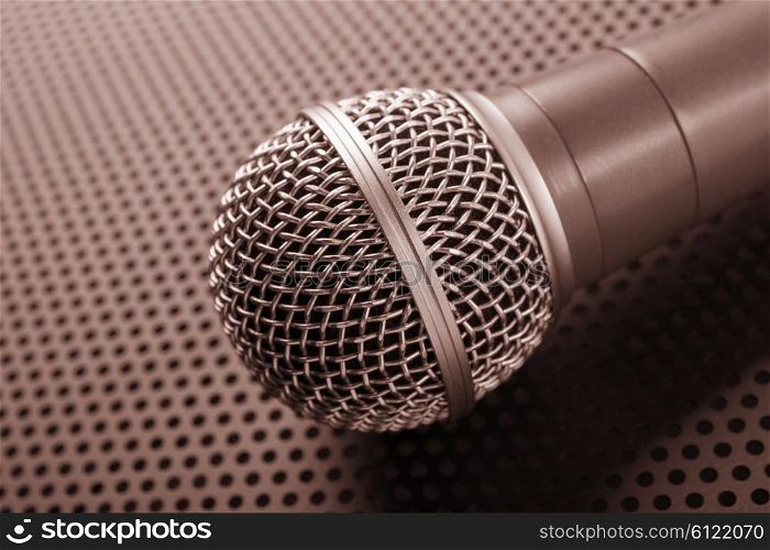 Classic dynamic microphone on background perforated. Toned