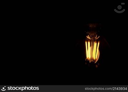 Classic Edison light bulb on black background with space for text.. Classic Edison light bulb on black background with space for text
