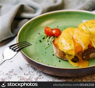 Classic egg benedict on green plate