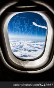 Classic image through aircraft window onto jet engine. Frost on the glass window. Focus on the wing of the aircraft.
