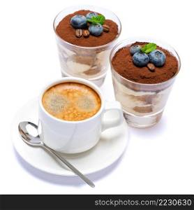 Classic italian tiramisu dessert with blueberries in a glass and cup of coffee isolated on a white background with clipping path. Classic tiramisu dessert with blueberries in a glass and cup of coffee isolated on a white background with clipping path