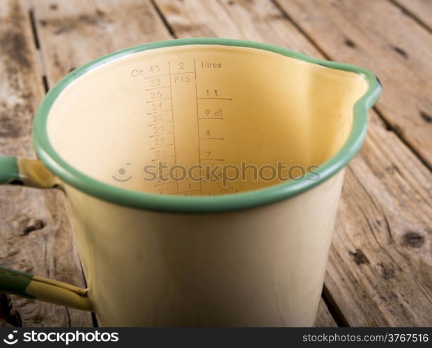 Classic old measuring jug in vintage colours in shallow focus on a wooden table