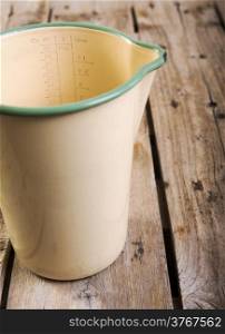 Classic old measuring jug in vintage colours in shallow focus on a wooden table