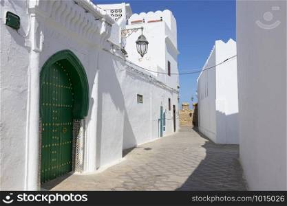 Classic old street in the medina of Asilah with the rampart wall at the end of the street, Northern Morocco