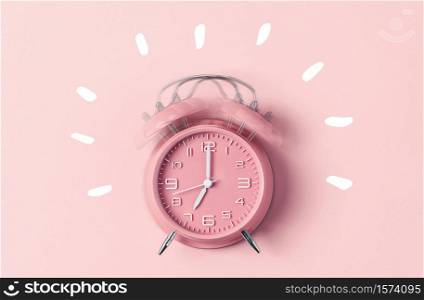 Classic pink alarm clock ringing at seven o&rsquo;clock against pastel pink background, copy space