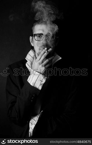 Classic portrait of young man in glasses with cigarette on black background