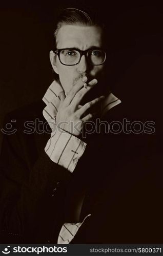 classic portrait of young man in glasses with cigarette on black background