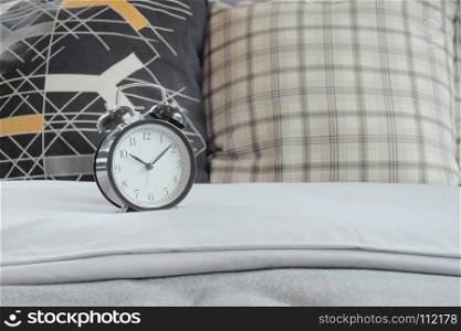 Classic style clock and pillows on white linen bedding