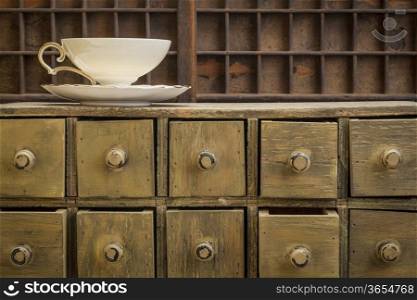classic tea cup on top of rustic apothecary drawer cabinet