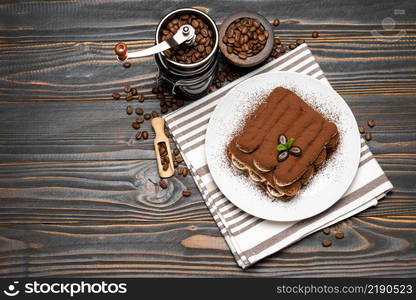 Classic tiramisu dessert and coffee grinder on ceramic plate on wooden background or table. Classic tiramisu dessert and coffee grinder on ceramic plate on wooden background