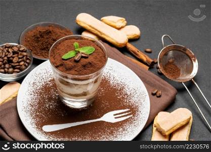 Classic tiramisu dessert in a glass and cup of coffee on dark concrete background or table. Classic tiramisu dessert in a glass and cup of coffee on dark concrete background