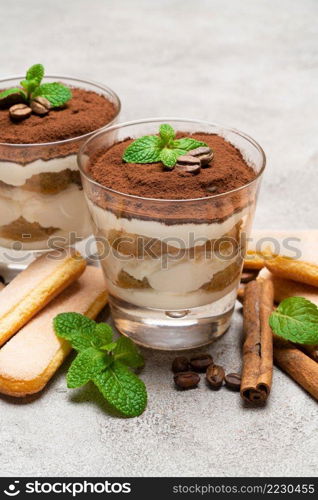 Classic tiramisu dessert in a glass and savoiardi cookies on concrete background or table. Classic tiramisu dessert in a glass and savoiardi cookies on concrete background