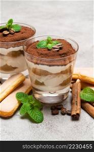 Classic tiramisu dessert in a glass and savoiardi cookies on concrete background or table. Classic tiramisu dessert in a glass and savoiardi cookies on concrete background