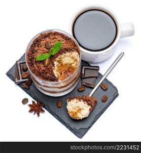 Classic tiramisu dessert in a glass cup and pieces of chocolate on stone cutting board on white background with clipping path embedded. Classic tiramisu dessert in a glass cup and pieces of chocolate on stone cutting board on white background with clipping path