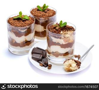 Classic tiramisu dessert in a glass cup on the plate and pieces of chocolate on white background with clipping path embedded. Classic tiramisu dessert in a glass cup on the plate and pieces of chocolate on white background with clipping path