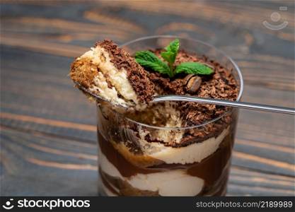 Classic tiramisu dessert in a glass cup on wooden background or table. Classic tiramisu dessert in a glass cup on wooden background