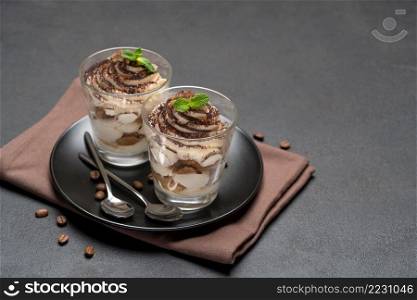 Classic tiramisu dessert in a glass on dark concrete background or table. Classic tiramisu dessert in a glass on dark concrete background