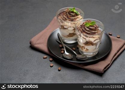 Classic tiramisu dessert in a glass on dark concrete background or table. Classic tiramisu dessert in a glass on dark concrete background