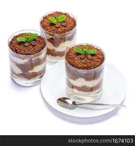 Classic tiramisu dessert in a glass on plate with spoon isolated on a white with clipping path embeeded. Classic tiramisu dessert in a glass on plate with spoon isolated on a white with clipping path