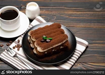 Classic tiramisu dessert on ceramic plate and cup of coffee on wooden background or table. Classic tiramisu dessert on ceramic plate, milk or cream and cup of coffee on wooden background