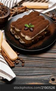Classic tiramisu dessert on ceramic plate and savoiardi cookies on wooden background or table. Classic tiramisu dessert on ceramic plate and savoiardi cookies on wooden background