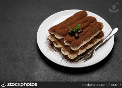 Classic tiramisu dessert on ceramic plate on dark concrete background or table. Classic tiramisu dessert on ceramic plate on dark concrete background