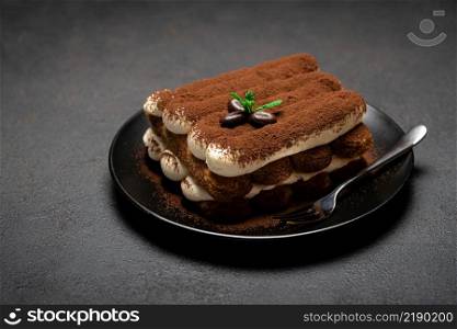 Classic tiramisu dessert on ceramic plate on dark concrete background or table. Classic tiramisu dessert on ceramic plate on dark concrete background