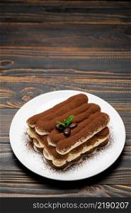 Classic tiramisu dessert on ceramic plate on wooden background or table. Classic tiramisu dessert on ceramic plate on wooden background
