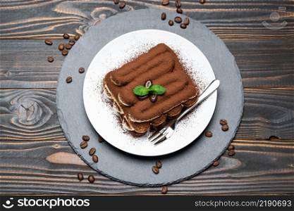 Classic tiramisu dessert on ceramic plate on wooden background or table. Classic tiramisu dessert on ceramic plate on wooden background