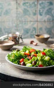 Classic vegetable salad with fresh olives, tomatoes, cucumbers and olive oil on gray background.. Classic vegetable salad