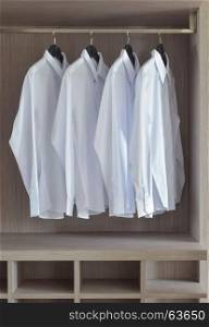 Classic white shirts in warm wooden wardrobe