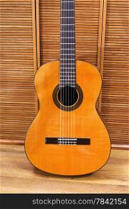 classical acoustic guitar near wooden wall
