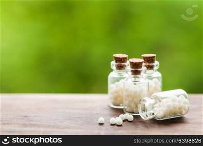 Classical Homeopathy globules in vintage bottles and nature leaves. Homeopathy pills in vintage bottles