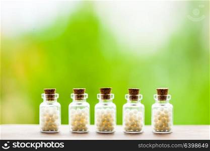 Classical Homeopathy globules in vintage bottles and nature leaves. Homeopathy pills in vintage bottles