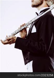 Classical music study concept. Male flutist musician performer playing flute. Young elegant man wearing tailcoat holds instrument. Male flutist wearing tailcoat holds flute