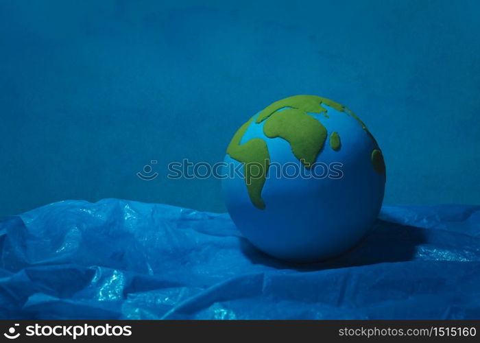 clay earth floating on blue plastic ocean