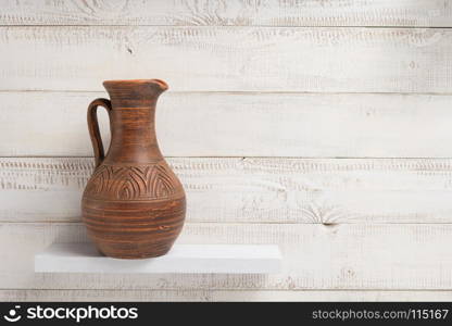 clay jug at shelf on white wooden plank background