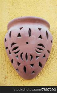 Clay oriental brown lamp on yellow decorative stucco wall.