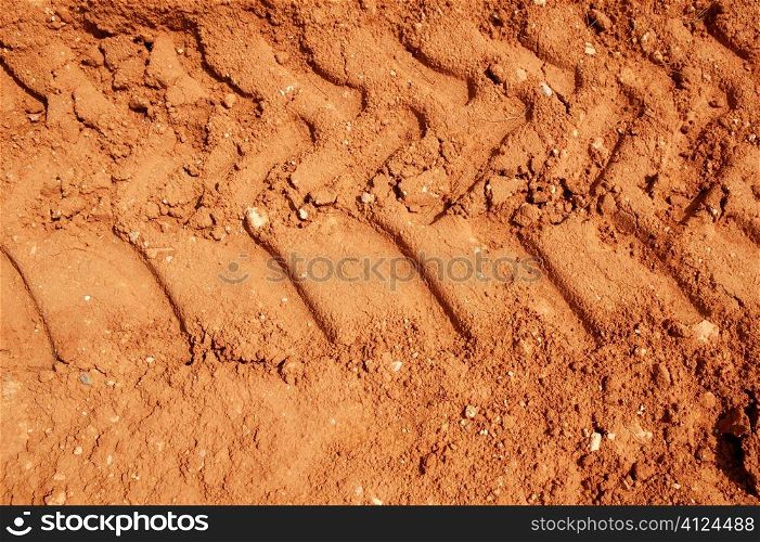 Clay red dried soil with tractor tires footprint