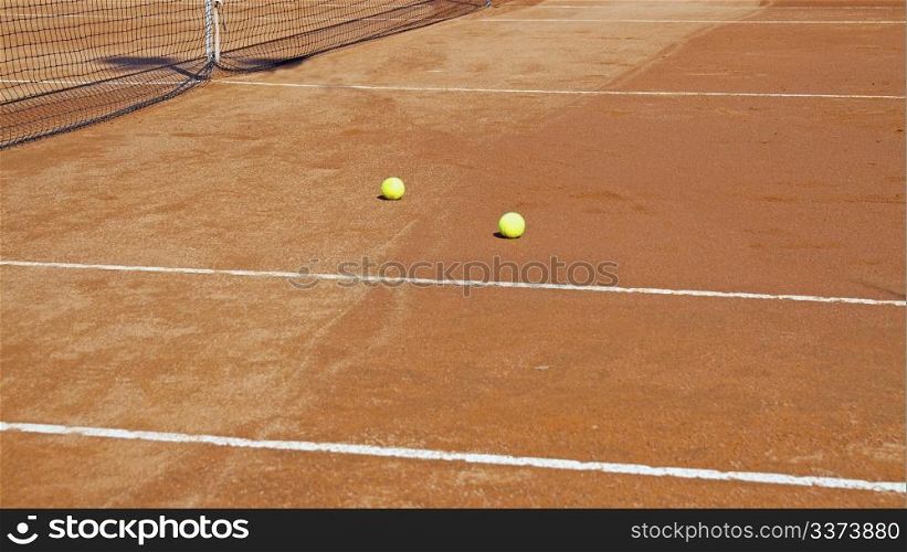 Clay tennis court with two yellow balls
