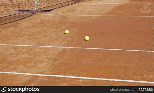 Clay tennis court with two yellow balls