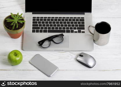 Clean and organized white desktop with office work objects and snacks. Layout in horizontal format.