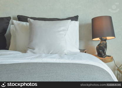 Clean bed in hotel guestroom with brown reading lamp