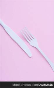 Clean new white knife and fork creative flat lay on trendy soft pink paper background