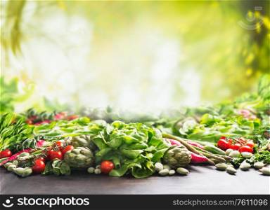 Clean organic farm vegetables background at sunny summer garden green nature background. Eco veggies . Healthy food concept. Tomato, lettuce, root vegetables,artichokes, asparagus,herbs,carrots.